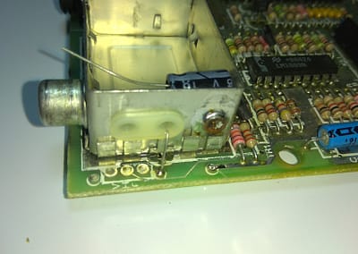 Introducimos el terminal positivo (+) de un condensador electrolítico de 100 uF por el pasacables de la antigua señal de vídeo compuesto y lo soldamos a la misma del PCB del spectrum.